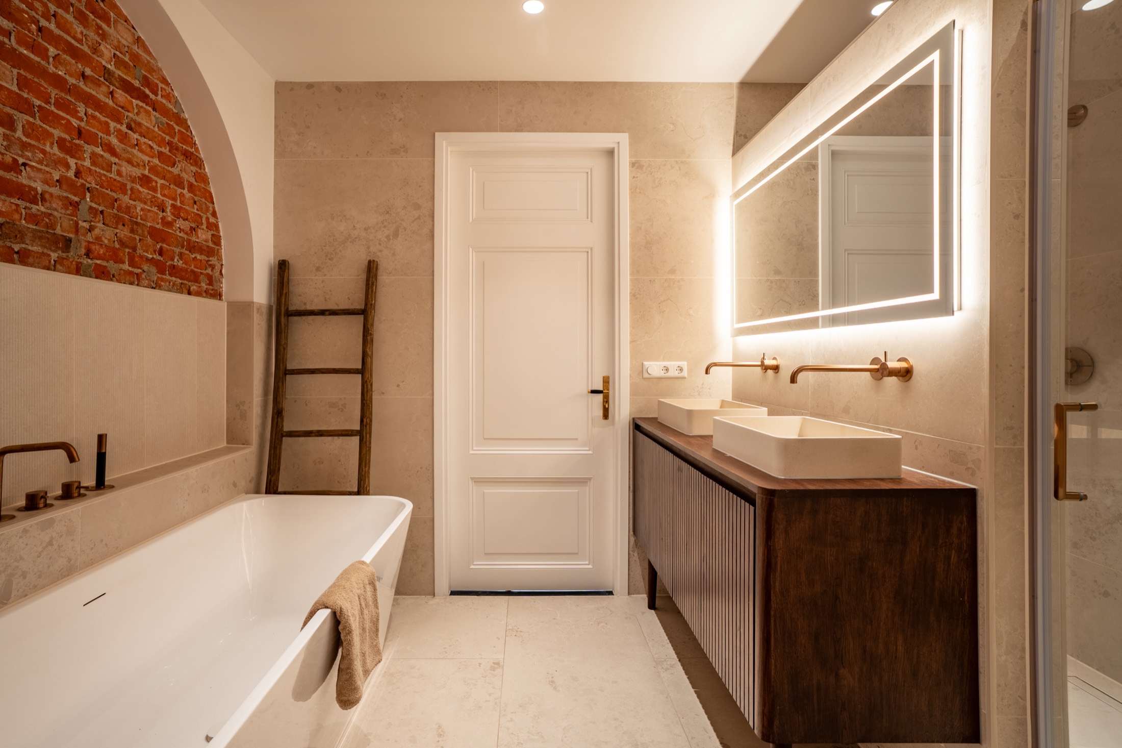 De badkamer met origineel metselwerk en vrijstaand bad